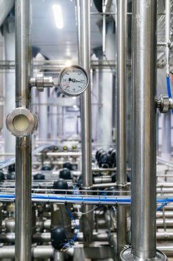 Modern bira fabrikasındaki büyük endüstriyel paslanmaz çelik borular ve basınç göstergesi..