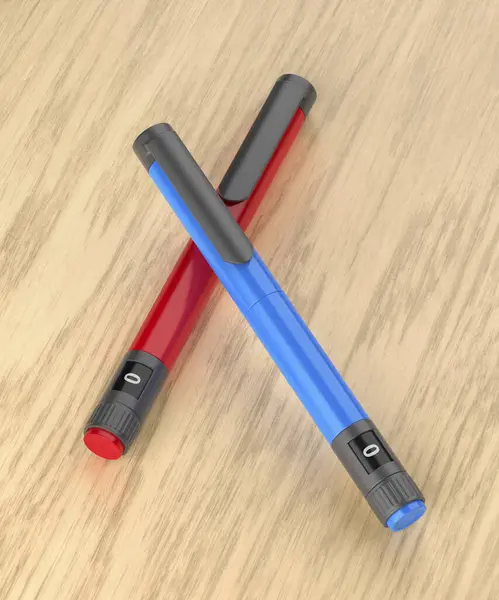 Blue and red insulin pens on wooden desk