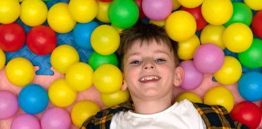 joyful boy among colored balloons