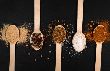 spoons with spices on a black background