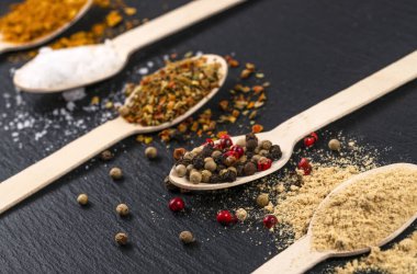 spices on wooden spoons on black board