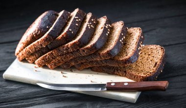 Siyah bir zemin üzerinde tahta bir tahta üzerinde siyah ekmek