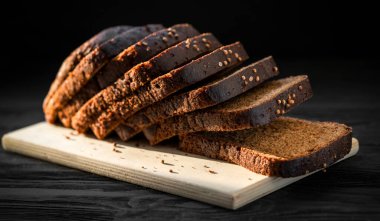 Siyah bir zemin üzerinde tahta bir tahta üzerinde siyah ekmek