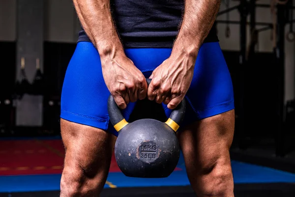 stock image Closeup of man holding heavy kettlebell at the gym.