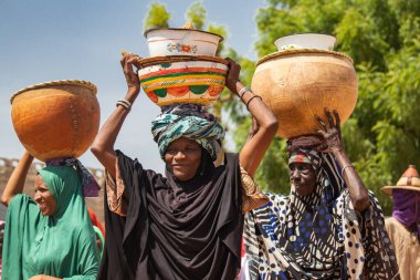 Afrika kabileleri, Nijerya, Borno Devleti, Maiduguri şehri. Geleneksel olarak renkli kıyafetler giyen Fulani kabile üyeleri, kafalarında su dolu kil ve metal kaplar.