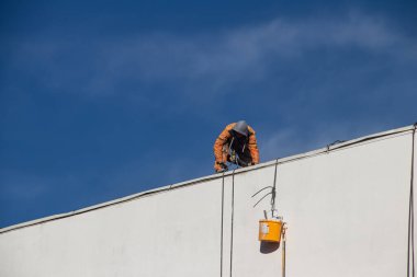 İnşaat işçisi, düşme önleme vücut kısıtlama sistemi, yüksek görüş mesafesi ceketinin altına takılan emniyet kemeri.