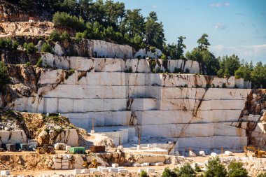 Daha fazla kullanım ve üretim için değerli taşı çıkarmak ve çıkarmak için kullanılan ağır makinelerle dolu beyaz mermer bir maden ocağı.