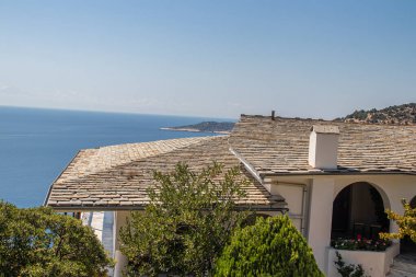 View on backyard of Monastery of Archangel Michael in Greece, Thasos Island, with vivid orange walls and roof, monastery was build at the cliff over the Aegean Sea, which first began as a men's only monastery at the start of the 20th century