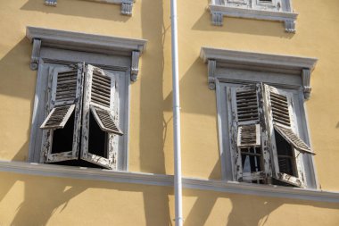 İtalya 'nın Trieste kentindeki sarı duvarda beyaz panjurlu geleneksel Akdeniz tarzı bina