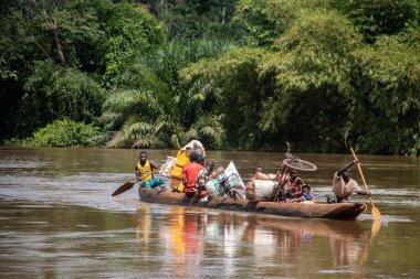 İnsanları Mbari Nehri 'nden yerel kanolarla ve feribotla geçirmek. Hafta sonu yerel pazardan satın alınan çeşitli ürünlerin rengarenk giysileri ve nakliyesi