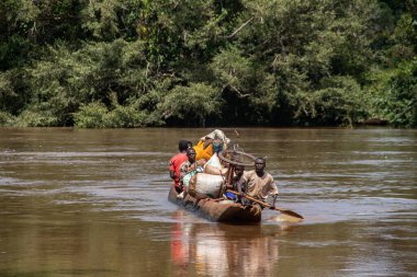 İnsanları Mbari Nehri 'nden yerel kanolarla ve feribotla geçirmek. Hafta sonu yerel pazardan satın alınan çeşitli ürünlerin rengarenk giysileri ve nakliyesi
