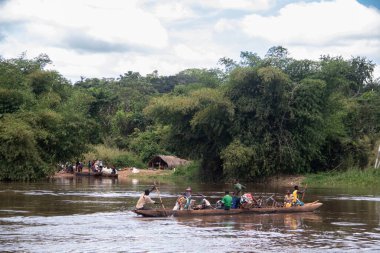 İnsanları Mbari Nehri 'nden yerel kanolarla ve feribotla geçirmek. Hafta sonu yerel pazardan satın alınan çeşitli ürünlerin rengarenk giysileri ve nakliyesi