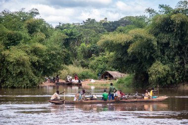 İnsanları Mbari Nehri 'nden yerel kanolarla ve feribotla geçirmek. Hafta sonu yerel pazardan satın alınan çeşitli ürünlerin rengarenk giysileri ve nakliyesi