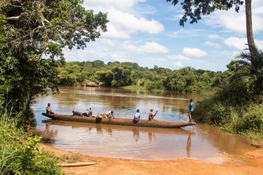 İnsanları Mbari Nehri 'nden yerel kanolarla ve feribotla geçirmek. Hafta sonu yerel pazardan satın alınan çeşitli ürünlerin rengarenk giysileri ve nakliyesi