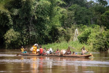 İnsanları Mbari Nehri 'nden yerel kanolarla ve feribotla geçirmek. Hafta sonu yerel pazardan satın alınan çeşitli ürünlerin rengarenk giysileri ve nakliyesi