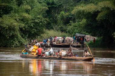 İnsanları Mbari Nehri 'nden yerel kanolarla ve feribotla geçirmek. Hafta sonu yerel pazardan satın alınan çeşitli ürünlerin rengarenk giysileri ve nakliyesi