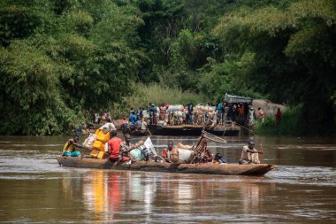 İnsanları Mbari Nehri 'nden yerel kanolarla ve feribotla geçirmek. Hafta sonu yerel pazardan satın alınan çeşitli ürünlerin rengarenk giysileri ve nakliyesi
