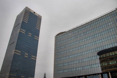 Şehir metropolü modern mimarisi. Dışarısı cam duvarlarla kaplı, etrafındaki binaları yansıtıyor. İş ve ofis amaçları için yepyeni binalar