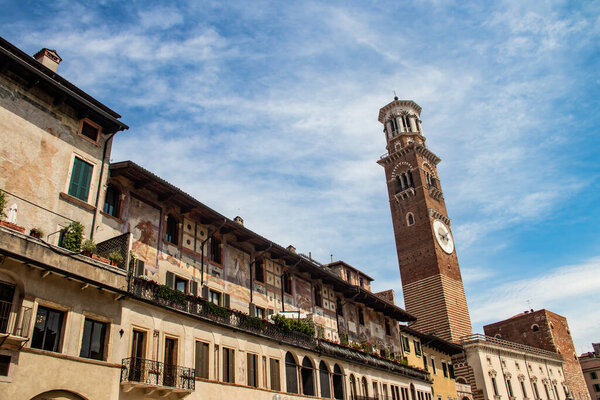 Medieval Lamberti (Torre dei Lamberti) tower XI century with clock, 84 metre and antica ancient column (1400 a.D) on Erbe Square in Verona city.