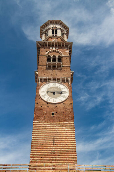 Medieval Lamberti (Torre dei Lamberti) tower XI century with clock, 84 metre and antica ancient column (1400 a.D) on Erbe Square in Verona city.
