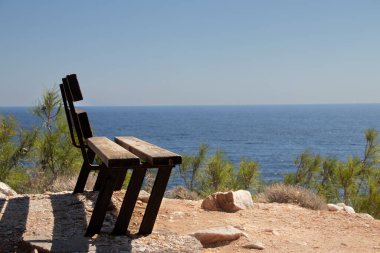 Deniz kenarındaki uçurumun kenarındaki yalnız ahşap bank, doğa ve çevreyle bağlantı kurmak için. 