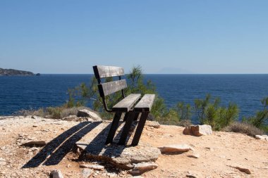 Deniz kenarındaki uçurumun kenarındaki yalnız ahşap bank, doğa ve çevreyle bağlantı kurmak için. 