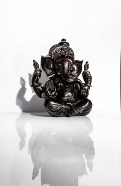Beyaz arkaplanı olan Ganesh 'in siyah heykelciği.