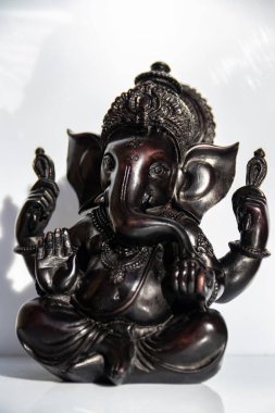 Beyaz arkaplanı olan Ganesh 'in siyah heykelciği.