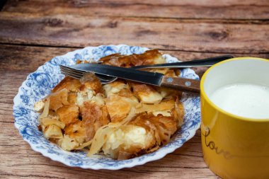 Sırp yemeği Burek (peynir turtası), kahvaltıda sofrada çatal bıçak takımı ve sarı fincanda taze yoğurt ile servis ediliyor. Sağlıklı besleyici yemek