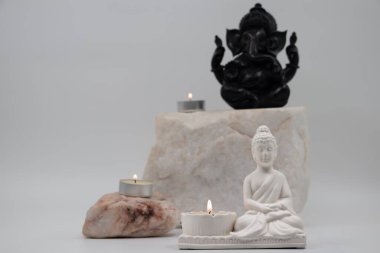 Siddhartha Gautama 'nın beyaz mermer heykelciğini kapatın, Buda olarak bilinir, mum yakma ve dekoratif çiçeklerle, renkli geleneksel arka planla