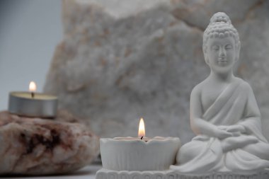 Siddhartha Gautama 'nın beyaz mermer heykelciğini kapatın, Buda olarak bilinir, mum yakma ve dekoratif çiçeklerle, renkli geleneksel arka planla