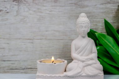 Siddhartha Gautama 'nın beyaz mermer heykelciğini kapatın, Buda olarak bilinir, mum yakma ve dekoratif çiçeklerle, renkli geleneksel arka planla