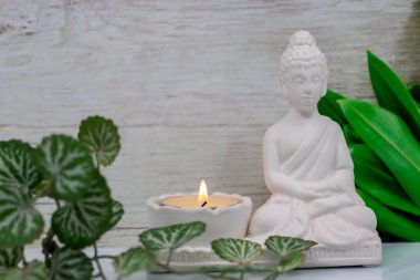 Siddhartha Gautama 'nın beyaz mermer heykelciğini kapatın, Buda olarak bilinir, mum yakma ve dekoratif çiçeklerle, renkli geleneksel arka planla