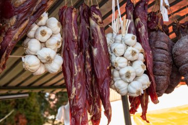 Kilerde kurutulmuş et, otlar ve taze sebzelerle sarımsak teli asılı.