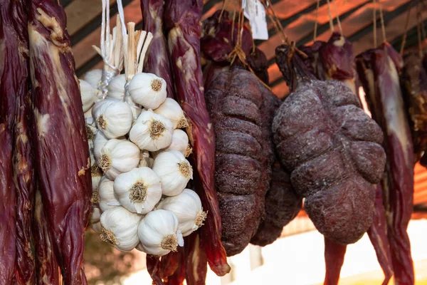 Garlic string with dried smoked meat and herbs and fresh vegetables hanging in the pantry