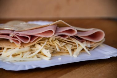 Jambon ve erimiş peynirle dolu leziz bir krep lezzetli bir lezzet kombinasyonu sunar. Gözlemenin altın gibi, çıtır çıtır dışı doyurucu ve doyurucu bir yemek için sıcak ve lezzetli bir dolgu içerir..