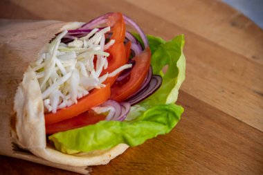 Lezzetli ve sağlıklı bir vejetaryen sandviçi. Çıtır yeşil salata yaprakları, sulu domatesler, lezzetli beyaz peynir ve leziz soğanlar, hepsi tatmin edici bir lokma için taze ekmek dilimlerinin arasına yerleştirilmiş..