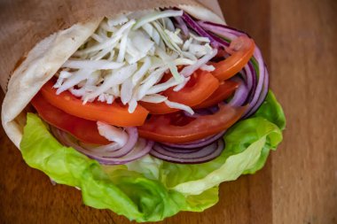 Lezzetli ve sağlıklı bir vejetaryen sandviçi. Çıtır yeşil salata yaprakları, sulu domatesler, lezzetli beyaz peynir ve leziz soğanlar, hepsi tatmin edici bir lokma için taze ekmek dilimlerinin arasına yerleştirilmiş..