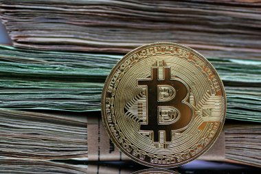 Altın Bitcoin paraları, modern finans sektöründe geleneksel ve dijital para birimi arasındaki etkileşimi sembolize eden bir yığın Euro banknotunun yanına yerleştirilmiştir.