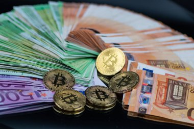 Altın Bitcoin paraları, modern finans sektöründe geleneksel ve dijital para birimi arasındaki etkileşimi sembolize eden bir yığın Euro banknotunun yanına yerleştirilmiştir.
