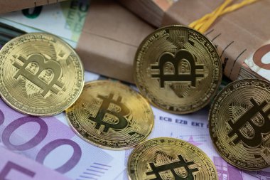 Altın Bitcoin paraları, modern finans sektöründe geleneksel ve dijital para birimi arasındaki etkileşimi sembolize eden bir yığın Euro banknotunun yanına yerleştirilmiştir.