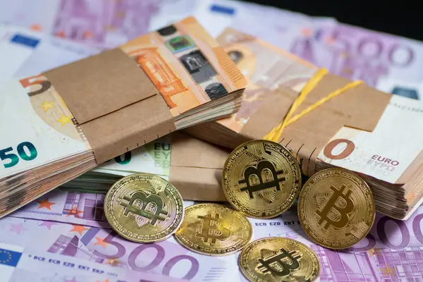 Altın Bitcoin paraları, modern finans sektöründe geleneksel ve dijital para birimi arasındaki etkileşimi sembolize eden bir yığın Euro banknotunun yanına yerleştirilmiştir.