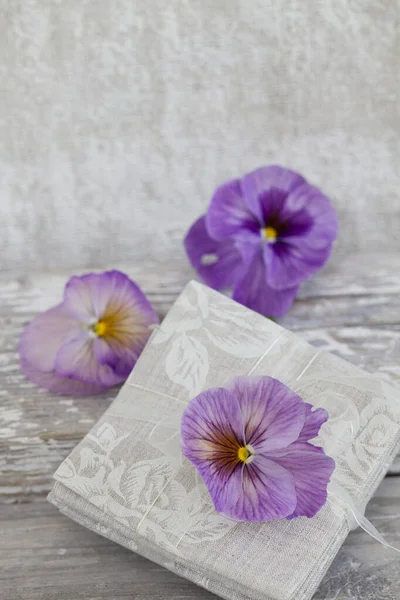 nostalgic still life with pastel purple pansie flowers and linen fabric, perfect for a greeting card, calendar image or gift bag