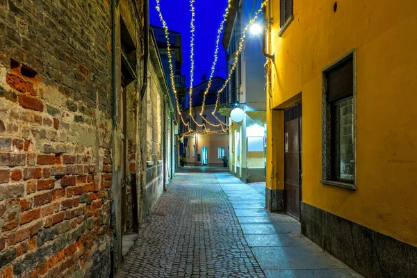 Wąska Brukowa Uliczka Wśród Starych Domów Oświetlonych Lampkami Świątecznymi Wieczorem — Zdjęcie stockowe