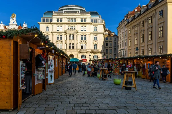 ウィーン オーストリア 2019年12月4日 ウィーンの旧市街で行われている有名なクリスマスマーケットで伝統的なお土産や装飾品を販売する木製のキオスクの間で石畳の通りを歩く人々 — ストック写真