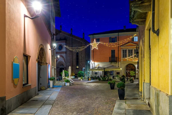 位于意大利北部皮埃蒙特阿尔巴的一座狭窄的鹅卵石街的景观和傍晚的圣诞照明 — 图库照片