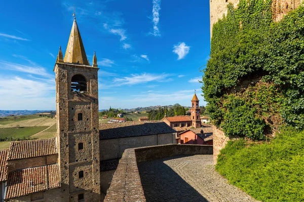 イタリアの小さな町Serralunga Albaで青い空の下で狭い石畳の通り 古い中世の鐘楼の景色 — ストック写真