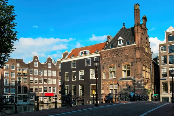 荷兰阿姆斯特丹典型的蓝天下老建筑和运河上的小桥景观 — 图库照片