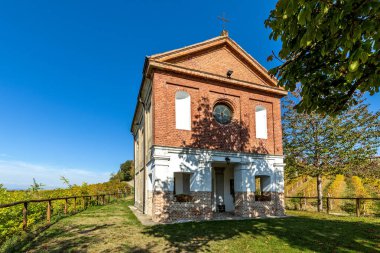 Kuzey İtalya, Piedmont 'ta mavi gökyüzünün altında renkli üzüm bağları arasında küçük bir şapel..