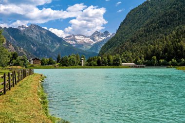 View of small alpine Lake Brusson and mountains under beautiful sky on background in Aosta Valley, Italy. clipart